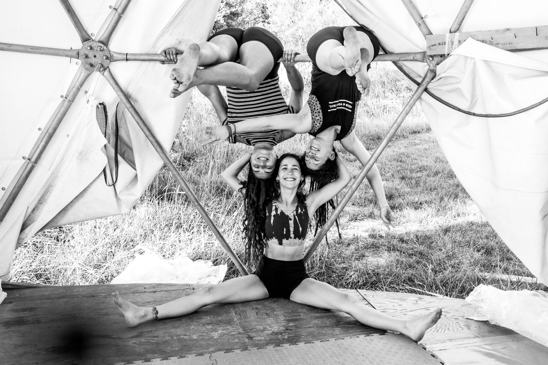 Tres personas riendo en un tríptico de AcroYoga: confianza y conexión